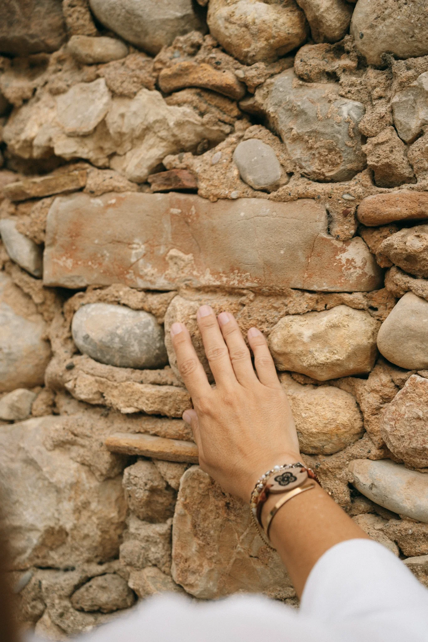 Detalle de una mano tocando la piedra original de Els Pallers
